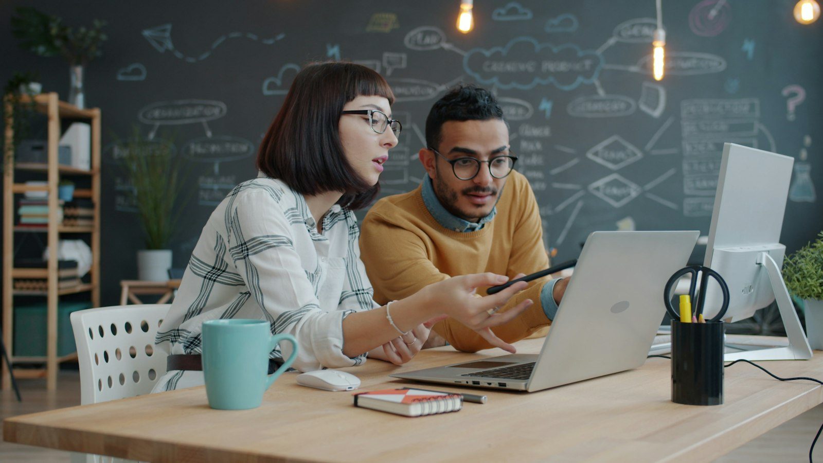 Two colleagues reviewing work on a laptop